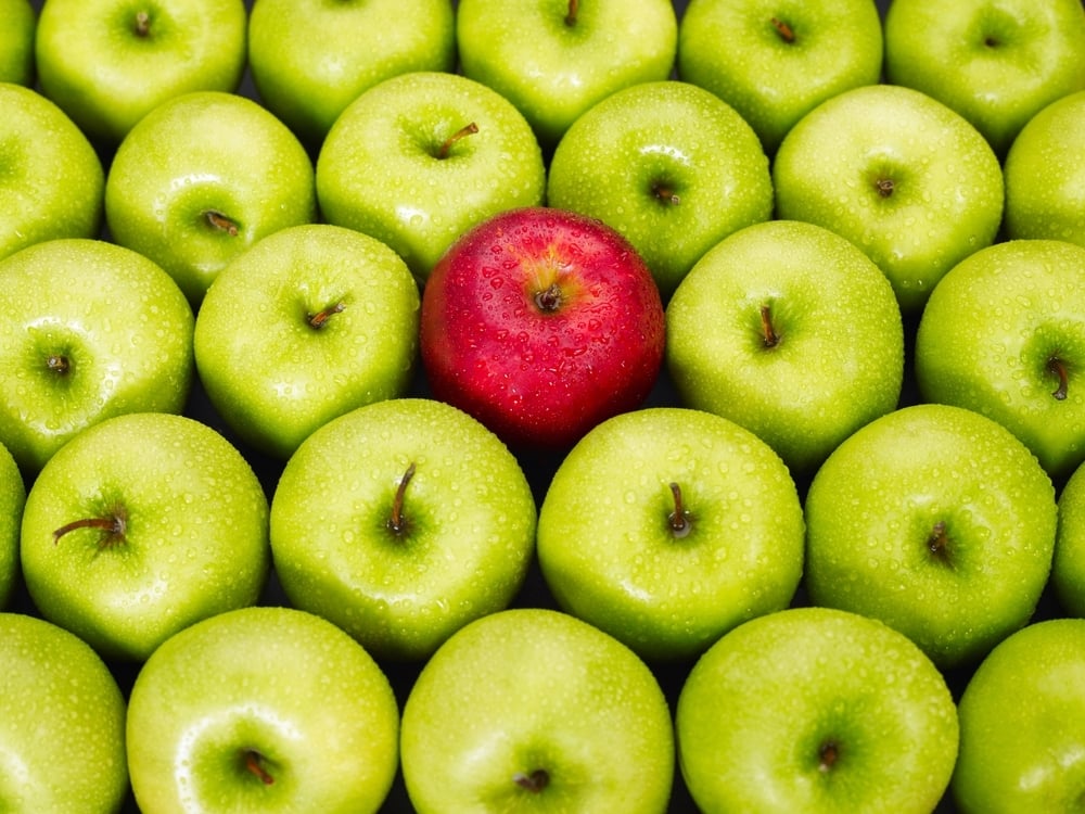 A red apple stands out among green competitors, cutting through the noise.