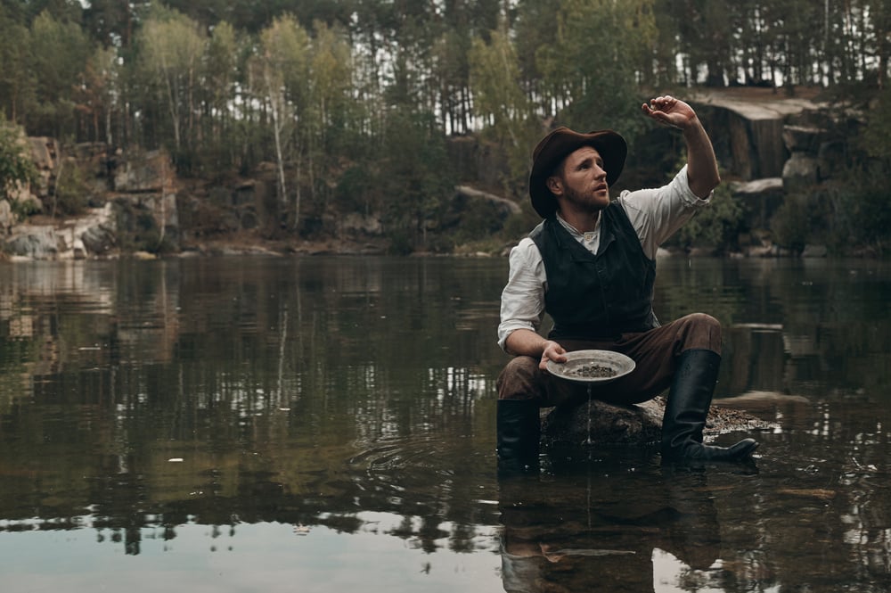 A prospector examines the gold nuggets he has found.