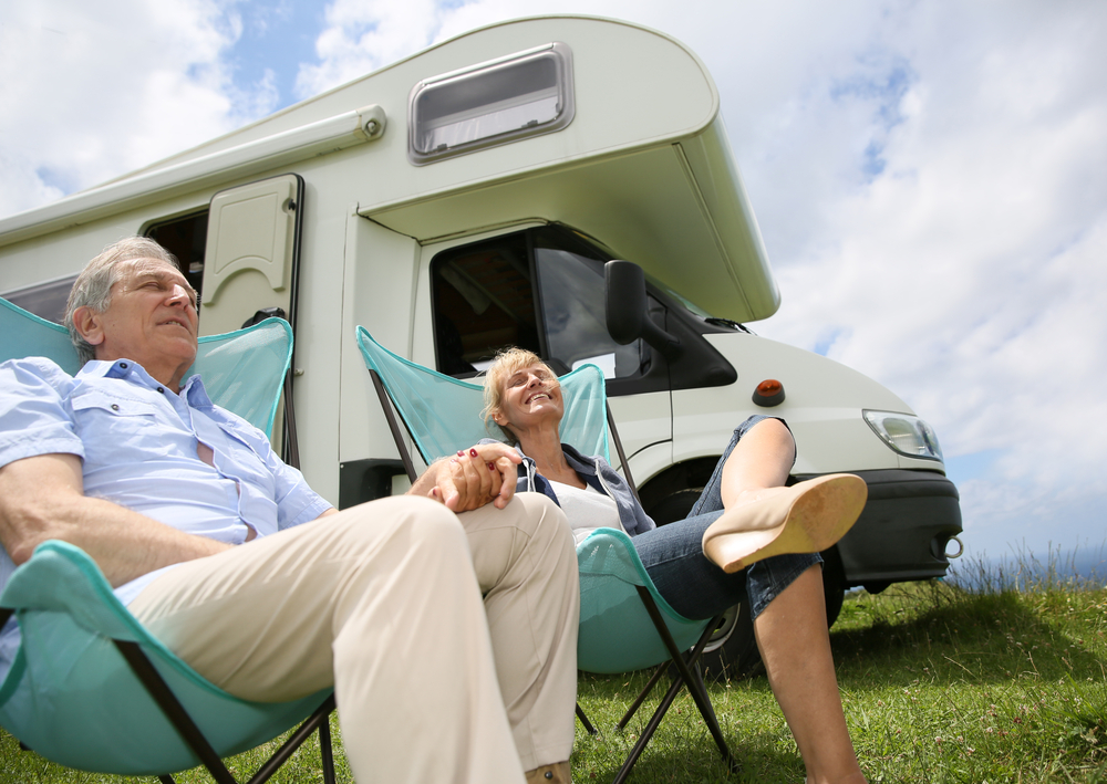 Retired couple sitting in chairs in front of camper